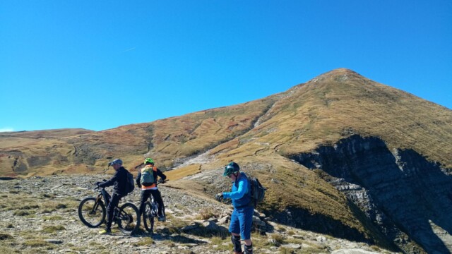 Gruppo di ciclisti in sosta lungo un sentiero roccioso con vista panoramica Laga selvaggia in MTB: Pizzo di Moscio, Cima Lepri e Cascata della Morricana